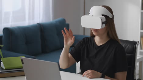 Junge-Frau-Schaut-Sich-Mit-VR-Headset-Den-Virtuellen-Bildschirm-An,-Während-Sie-Im-Wohnzimmer-Sitzt-Und-Auf-Die-Moderne-Technologie-Der-Virtuellen-Realität-Tippt